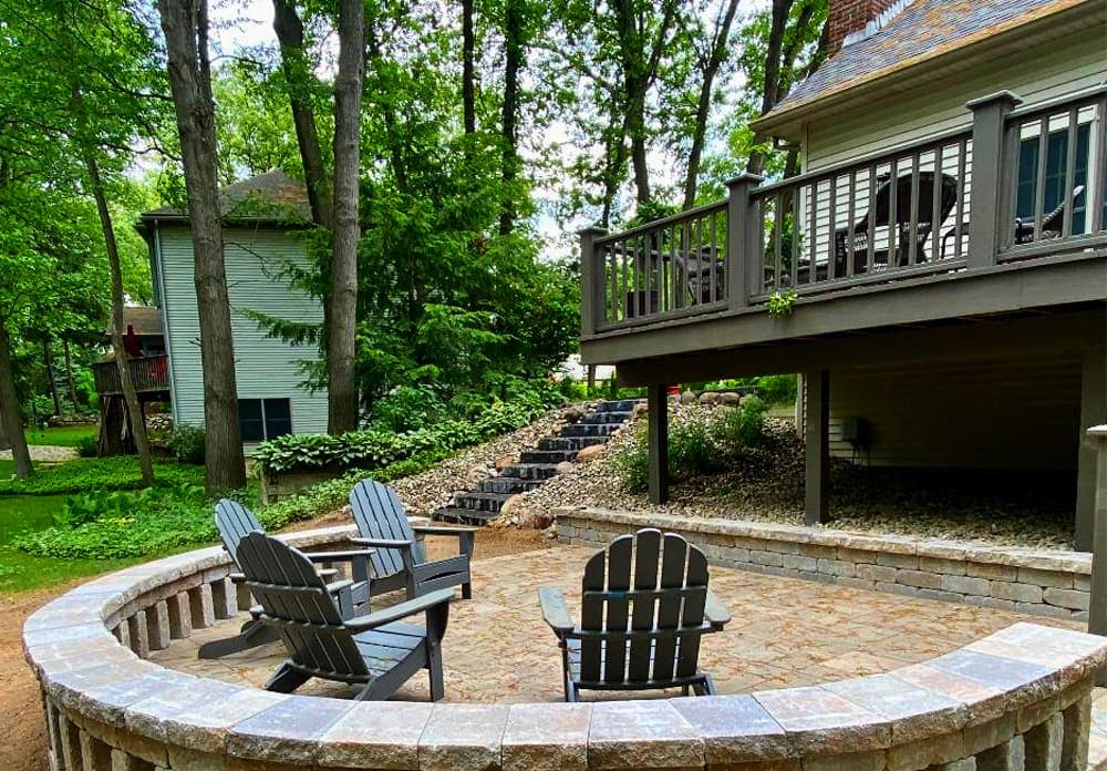 Cozy outdoor seating area with Adirondack chairs surrounded by lush greenery and stairs.
